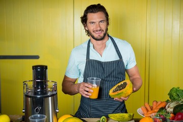 Portrait of smiling male staff holding glass of juice and papaya