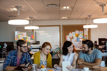 Creative business team discussing over digital tablet at desk