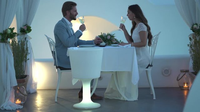 4k video newlywed couple sitting private dinner outside toasting with white wine
