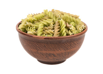 Green pasta fusilli in a bowl on white background