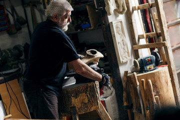 Senior sculptor working on his sculpture in his workshop.