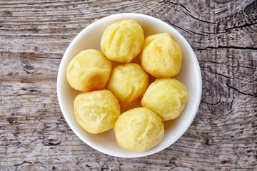 Bowl of potato balls on wood, from above