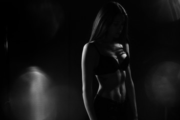 Black and white silhouette photo of a young girl in black lingerie and face in shadow.