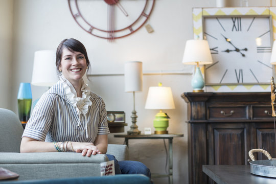 Portrait of smiling owner sitting on armchair in furniture store