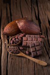 Chocolate bar and dried cocoa pod on wooden background