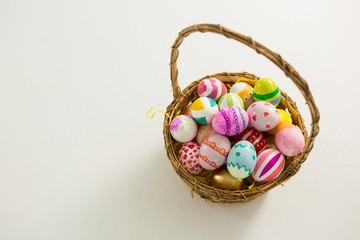 Basket with painted Easter eggs on white background