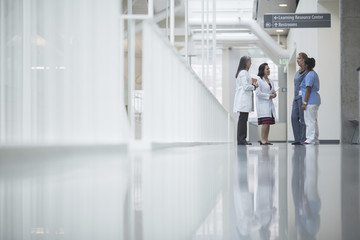Female doctors discussing while standing in hospital corridor