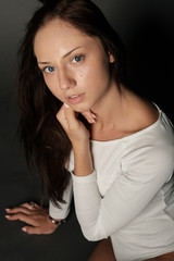 Close-up portrait of young brunette with blue eyes in a white bodysuit