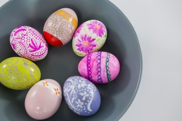 Bowl with painted Easter eggs on white background