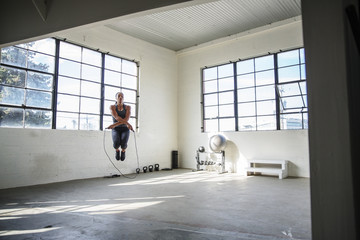 Female athlete skipping with jump rope in gym
