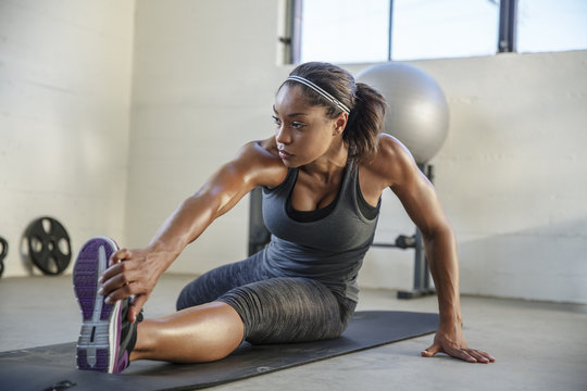 Athlete Stretching Legs On Exercise Mat In Gym