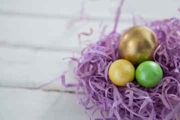 Golden Easter egg with two painted eggs in nest