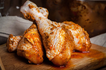 Marinated chicken drumsticks on a wooden chopping board.