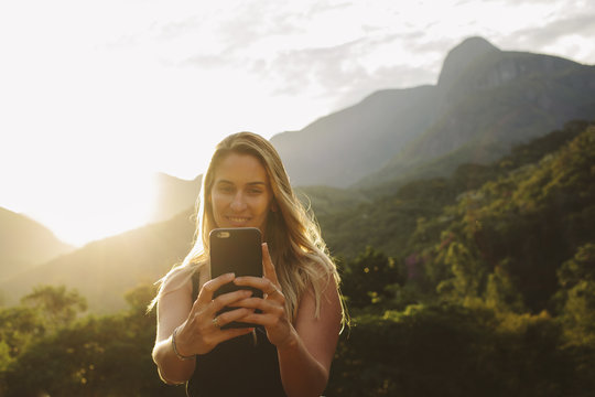 Smiling woman taking selfie while standing against mountains