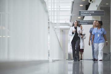 Female doctors discussing while walking in hospital corridor