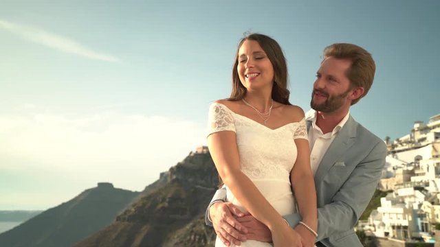 4k travel video beautiful dressed young couple together outside on island of santorin hugging and kissing at sunny afternoon
