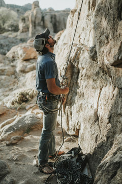 Hiker Looking Up While Holding Climbing Rope By Mountain