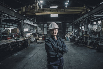 Portrait of confident female worker with arms crossed standing in factory