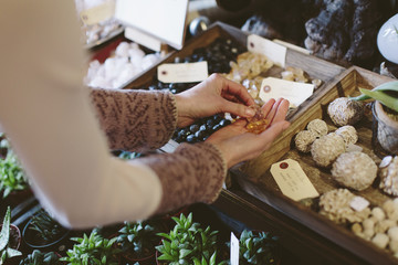 Cropped hands of owner holding stones over fertilizer balls at plant shop