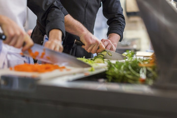 Midsection of chefs chopping vegetables at restaurant kitchen