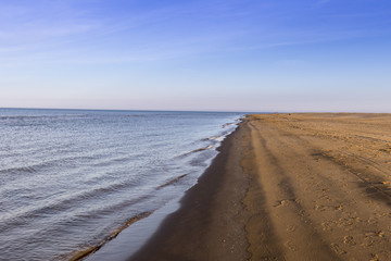 Orilla de mar y arena con horizonte rojizo al fondo