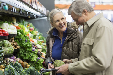 Smiling senior couple shopping for vegetables at supermarket