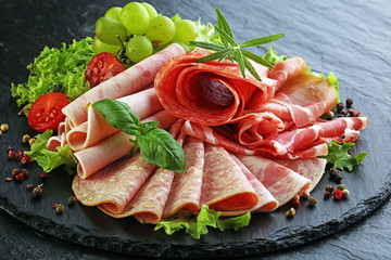 Food tray with delicious salami, pieces of sliced ham, sausage, tomatoes, salad and vegetable - Meat platter with selection