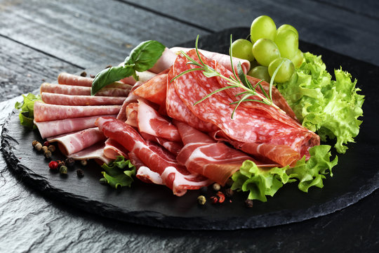 Food tray with delicious salami, pieces of sliced ham, sausage, tomatoes, salad and vegetable - Meat platter with selection