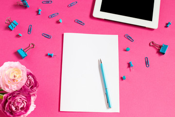 Stationery on a pink background. Paper clips and binders