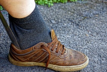 надевание обуви на ногу с помощью железной лопатки