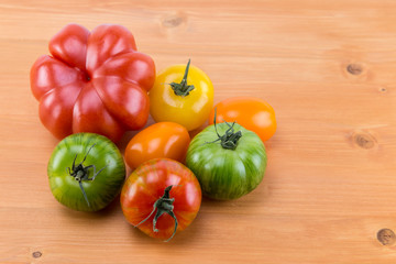 Different sorts of tomatoes on an oak natural wood table