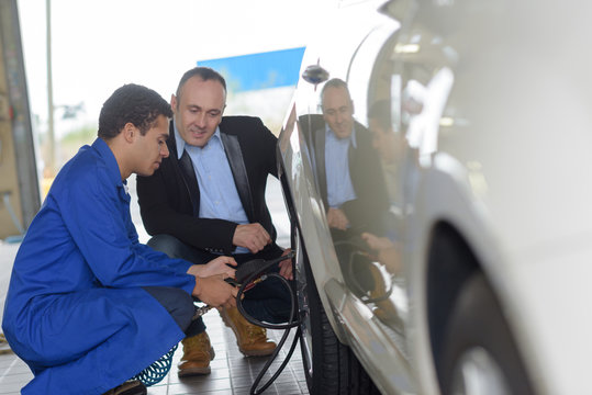 Mechanic Checking Car's Tyre Pressure With Client