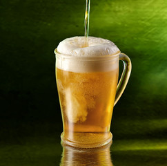 A glass of beer on a green background.