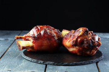 Smoked ham hock with herbs and spices on wooden plate.