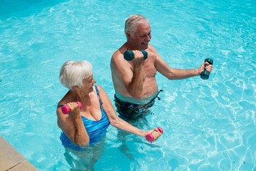 Senior couple exercising with dumbbells in the pool