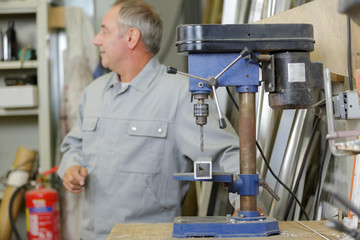 a man in the background using a milling machine
