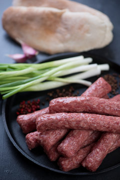 Close-up of balkan traditional cevapi or cevapcici sausages ready to be cooked, selective focus, vertical shot