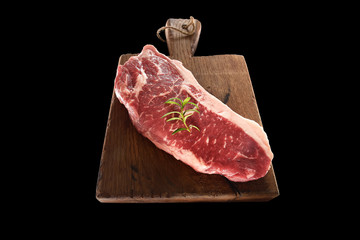 Raw marbled beef on a cutting board. On a black background