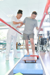 Physiotherapist helping man to walk