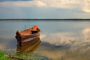One wooden fishing boat on bank of the lake. Spring landscape photo. Volyn region. Ukraine
