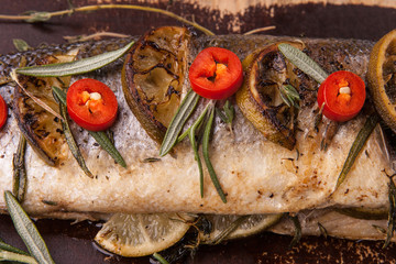 Part of the fish with filling, stuffed with vegetables and lime on cutting board. Top view