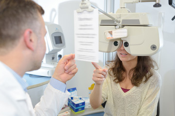 male optometrist examining young patient on phoropter