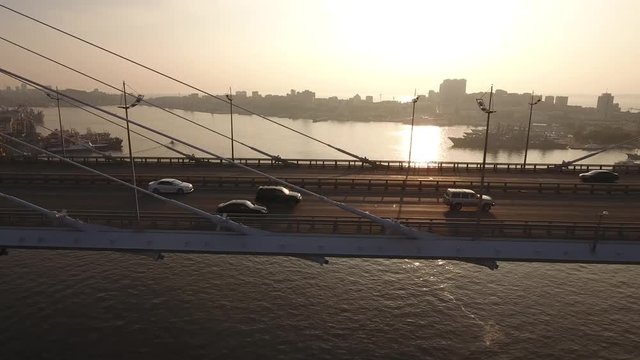 Follow cars on Golden Bridge cable-stayed across Zolotoy Rog road city traffic. Modern Vladivostok, Russia from above. Best unique Aerial drone helicopter flight 4k footage. Summer sunset orange. 