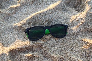 Fototapeta na wymiar Travel to island Phuket, Thailand. The sunglasses on the sand in the sunny weather.