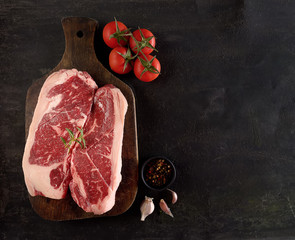Raw marbled beef on a cutting board. On a black background
