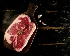 Raw fresh marbled meat Black Angus Steak and rosemary on dark wooden background