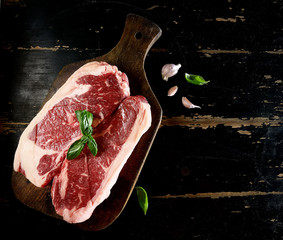 Raw marbled beef on a cutting board. On a black background
