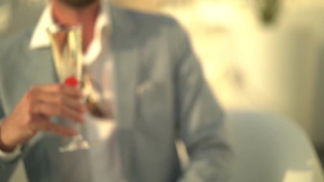 4k video detail man in fine suit cheering glasses with sparkling wine outside at sunset
