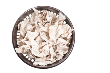 Crumpled toilet paper in a crowded trash can, top view, isolated on white background