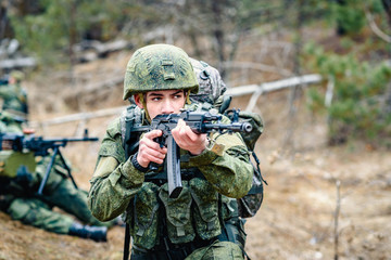 Fototapeta premium Portrait of a soldier of the Russian army with an automatic weapon in his hands, takes aim. Operation against terrorism